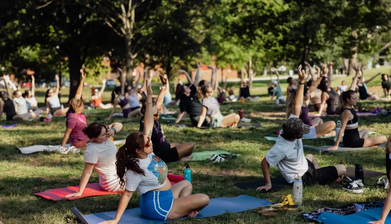 people seated doing yoga in the grass