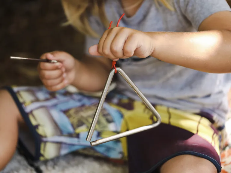 Child playing triangle instrument